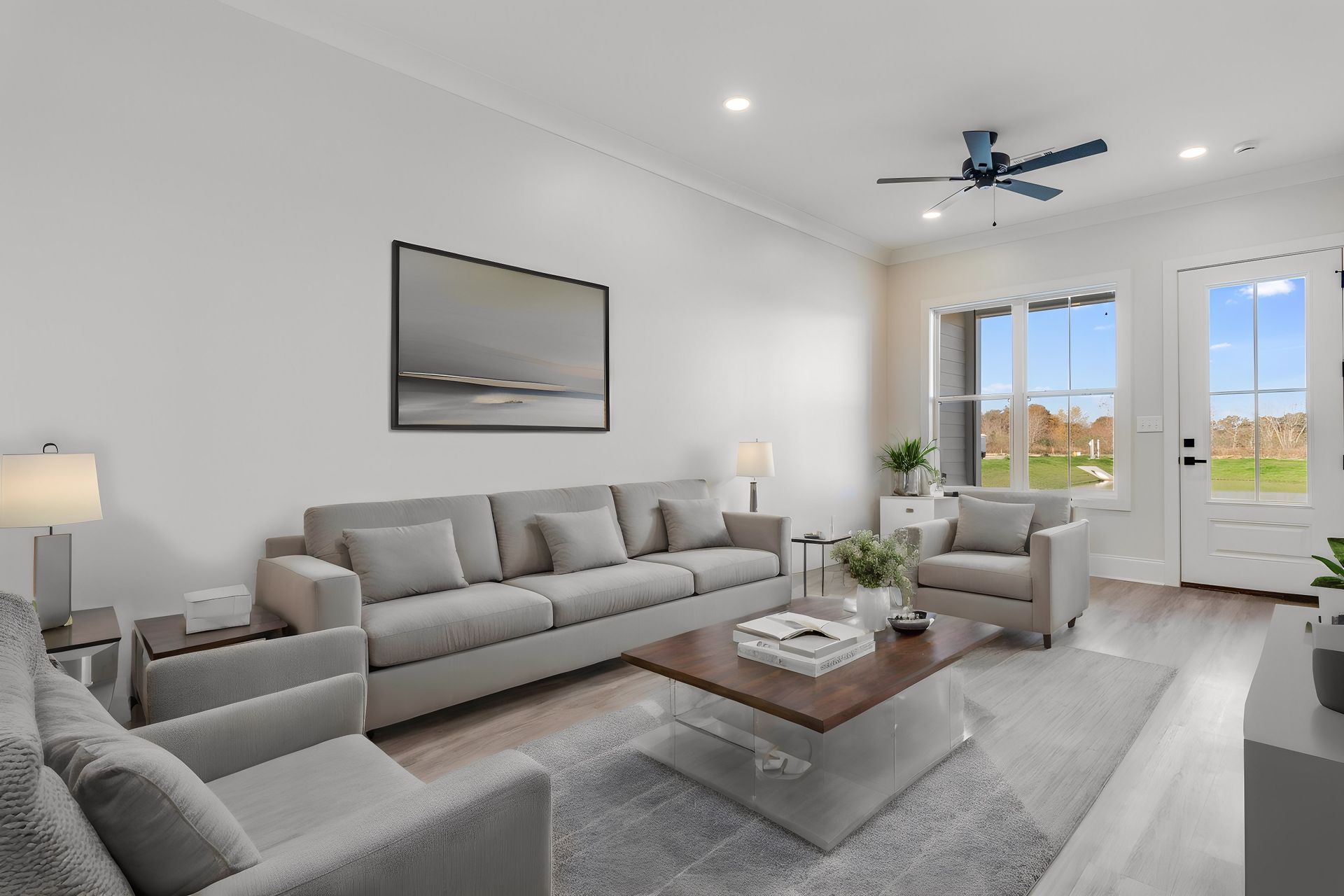 A living room with a couch , two chairs , a coffee table and a ceiling fan.