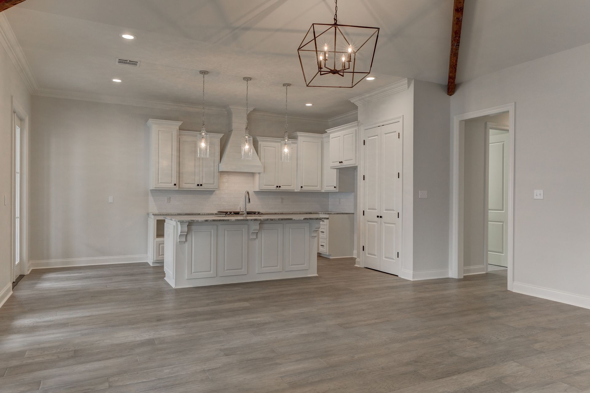 An empty kitchen with white cabinets and a large island.