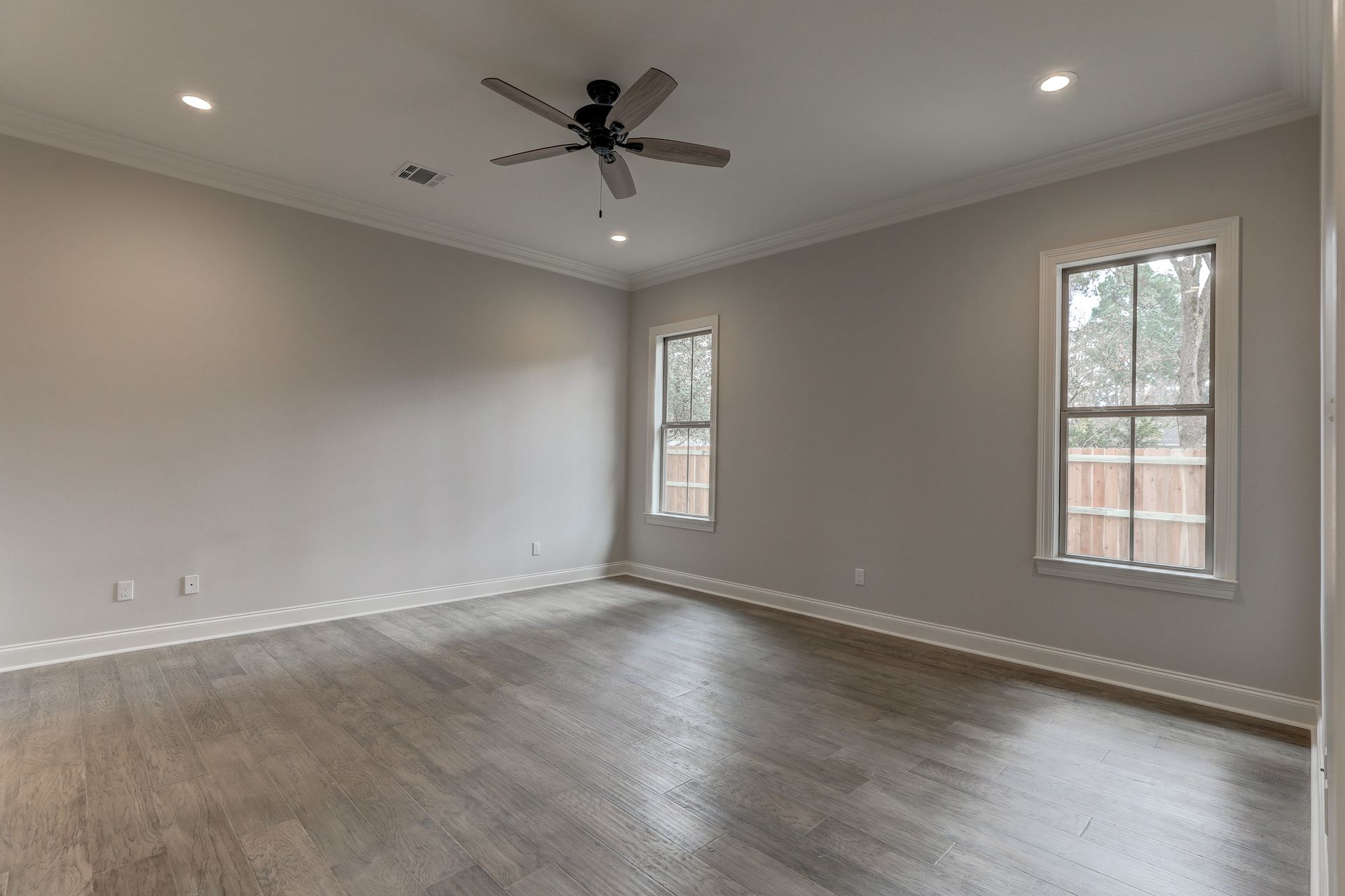 An empty living room with hardwood floors and a ceiling fan.