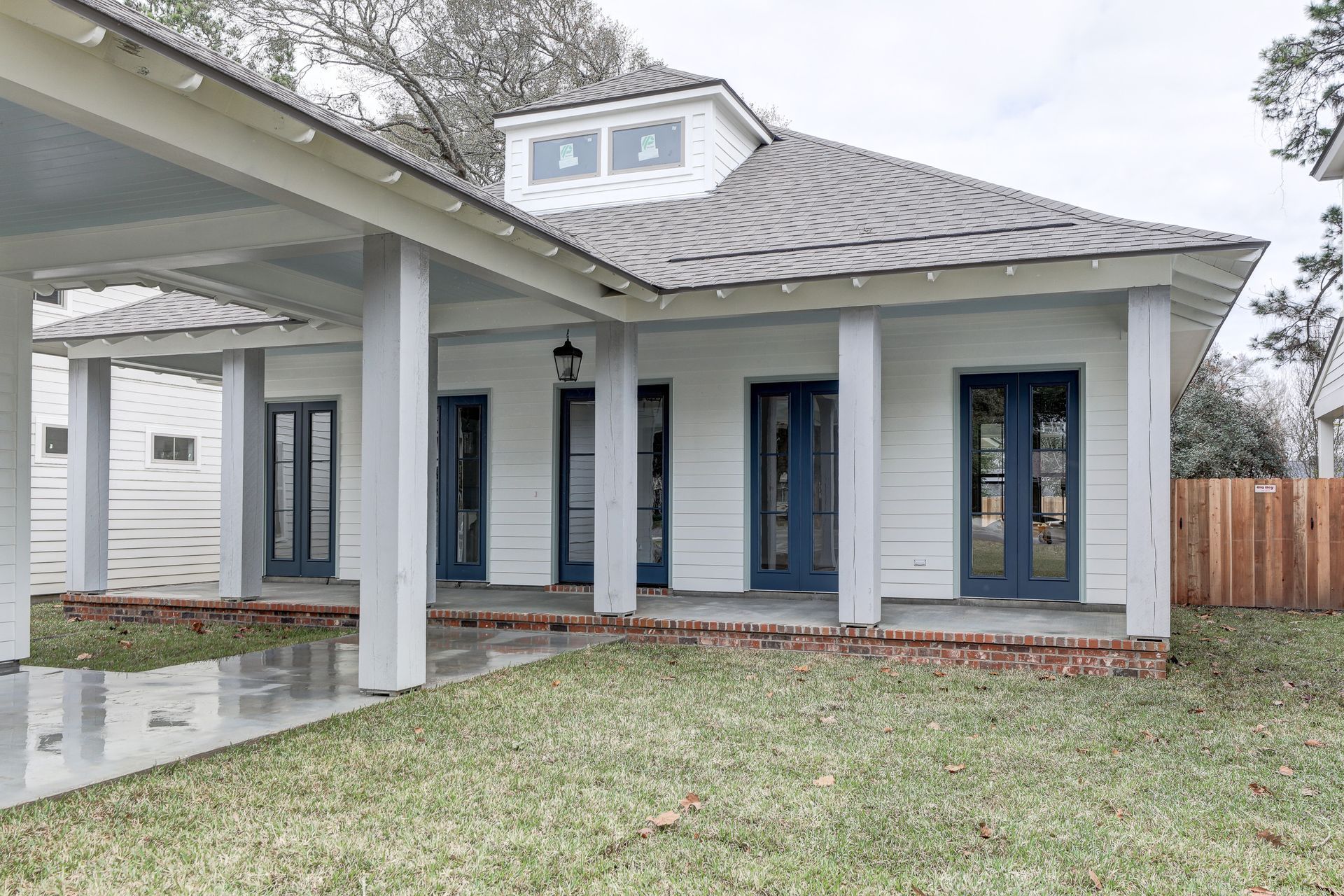 A white house with blue doors and a covered porch.