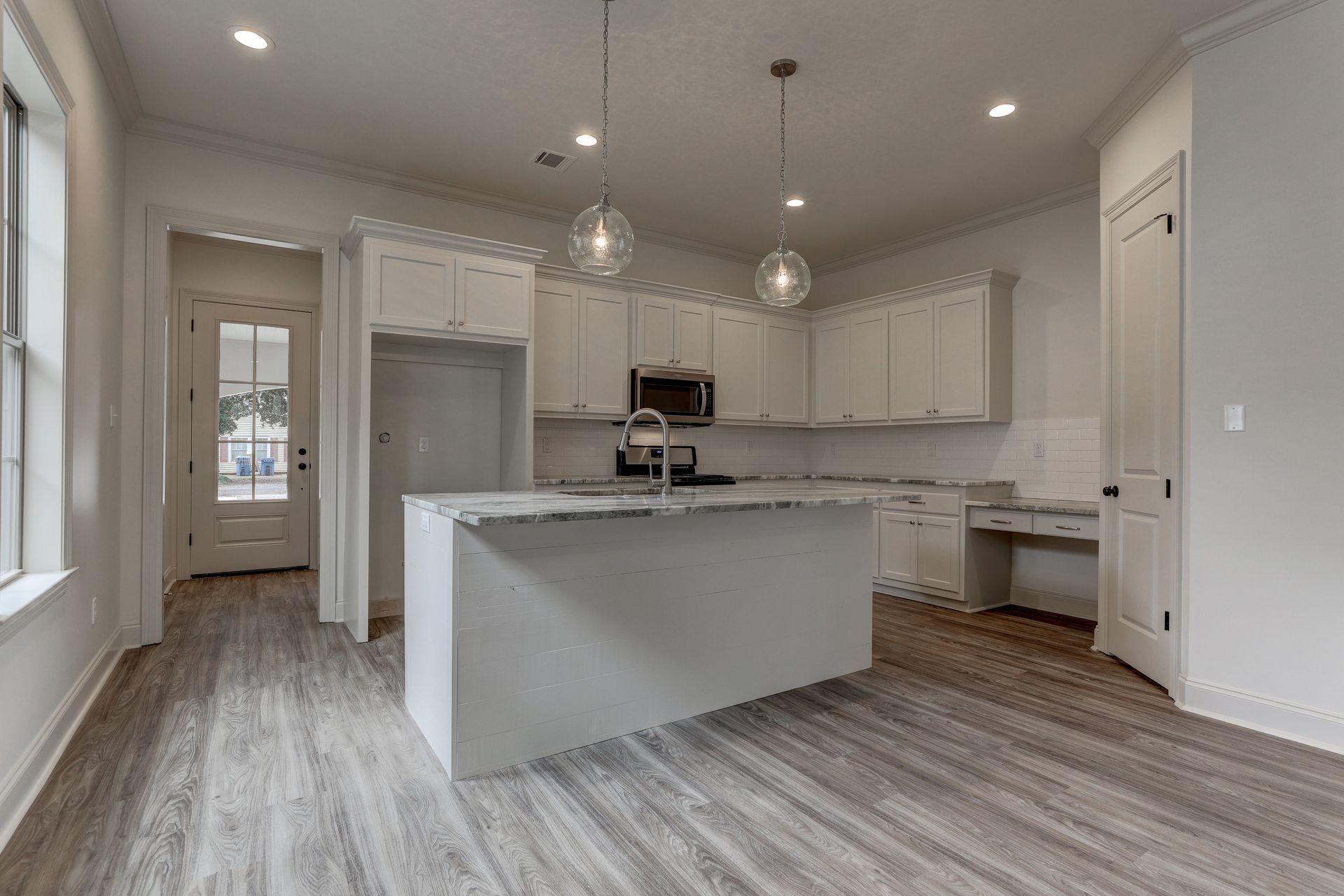 An empty kitchen with white cabinets and a large island.