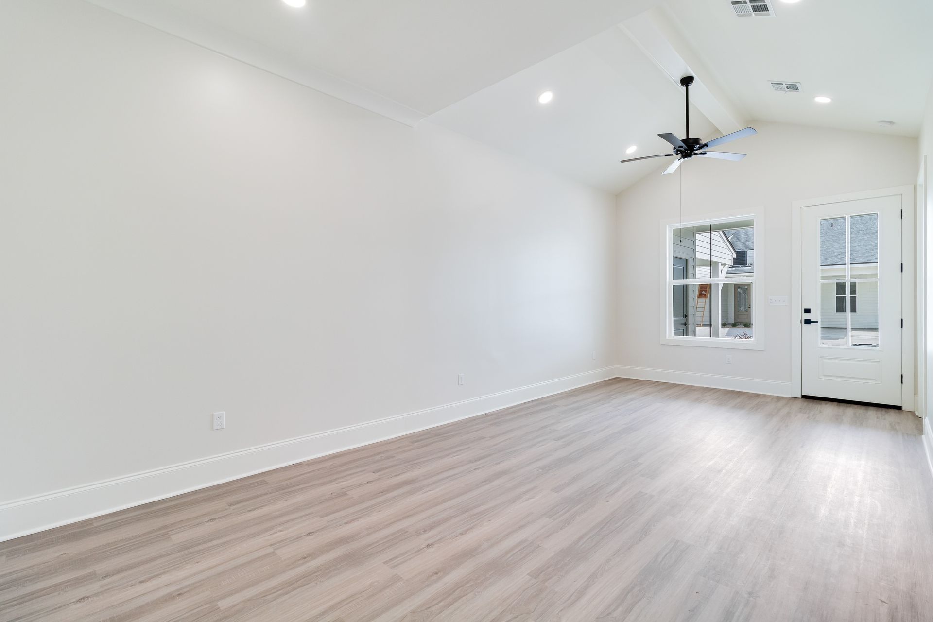 An empty living room with hardwood floors and a ceiling fan.