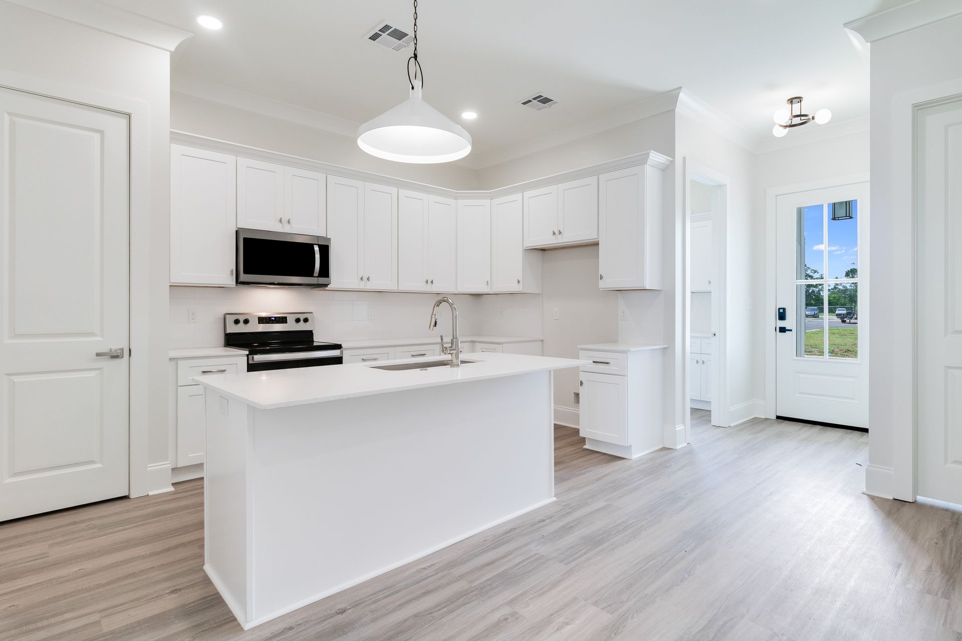 A kitchen with white cabinets , stainless steel appliances , and a large island.