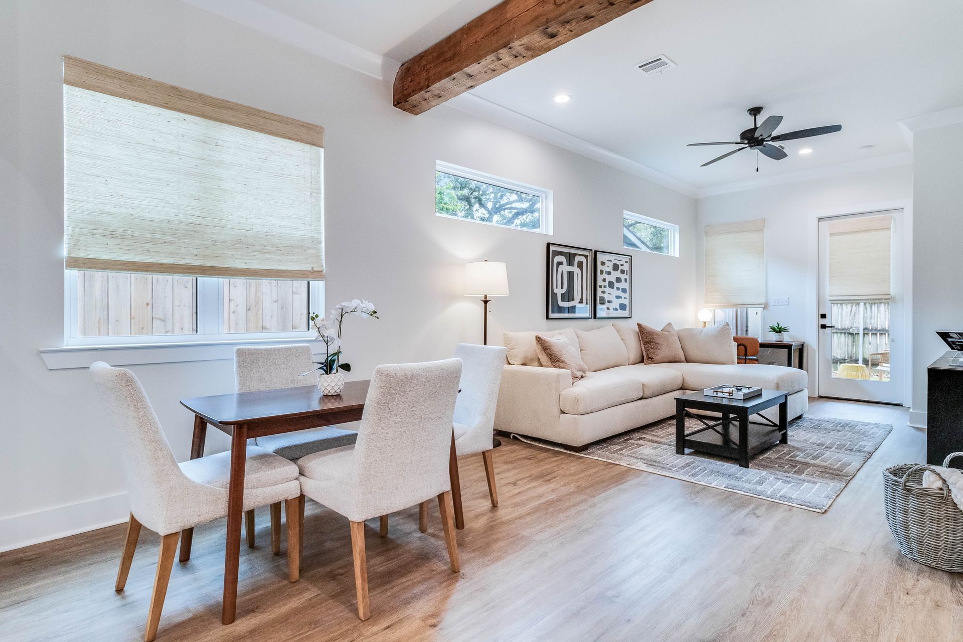 A living room with a couch , table , chairs and a ceiling fan.