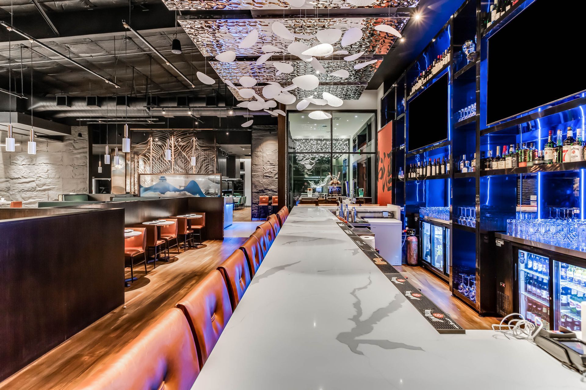 A long bar in a restaurant with a lot of bottles on the shelves.