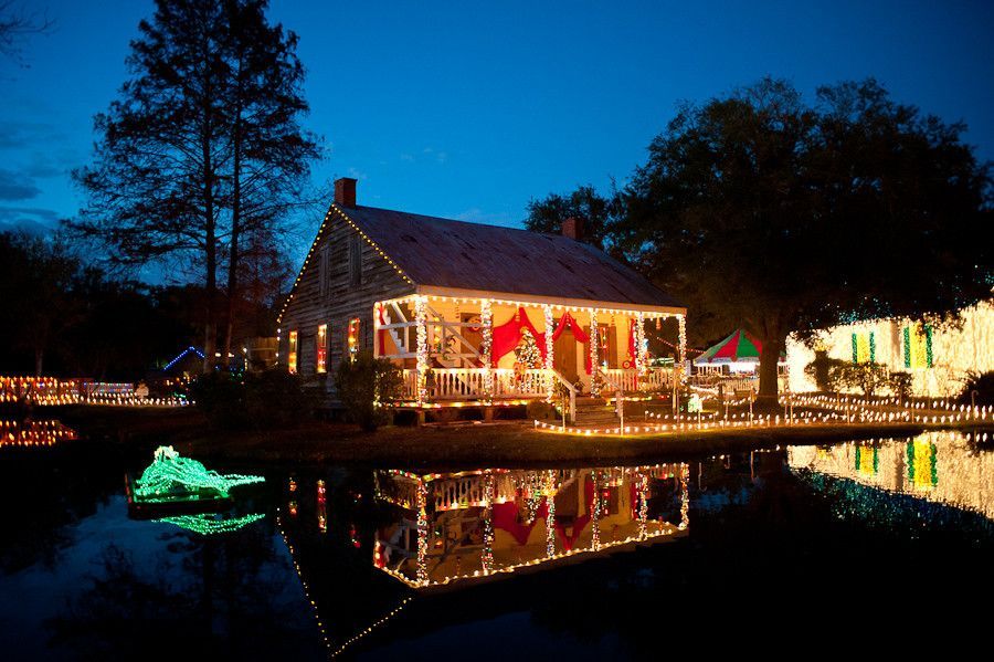 Christmas lights and a decorated Cajun home reflected on the water at Acadian Village during Noël Acadien au Village in Lafayette, Louisiana.