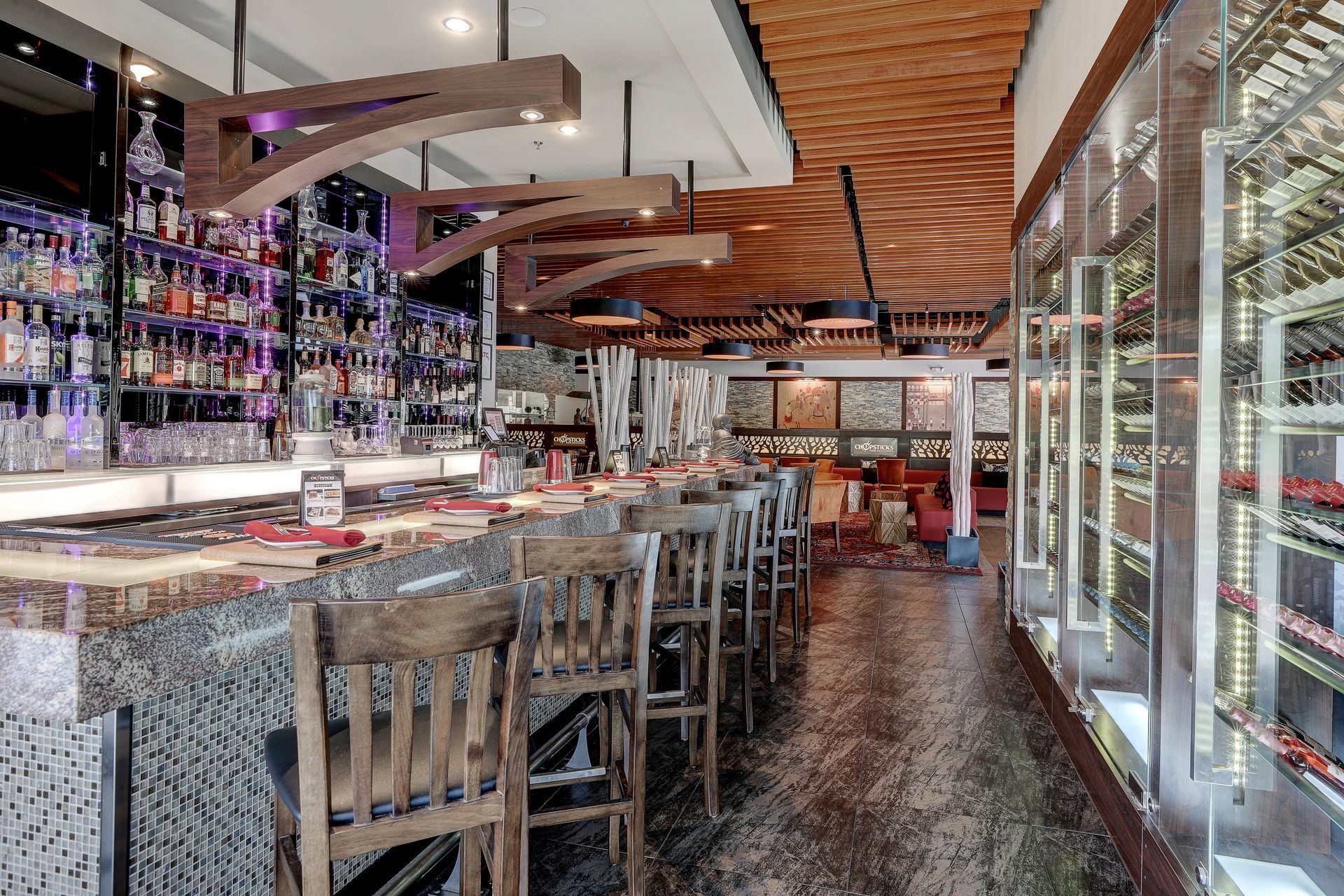 A restaurant with a long bar and lots of wine bottles.