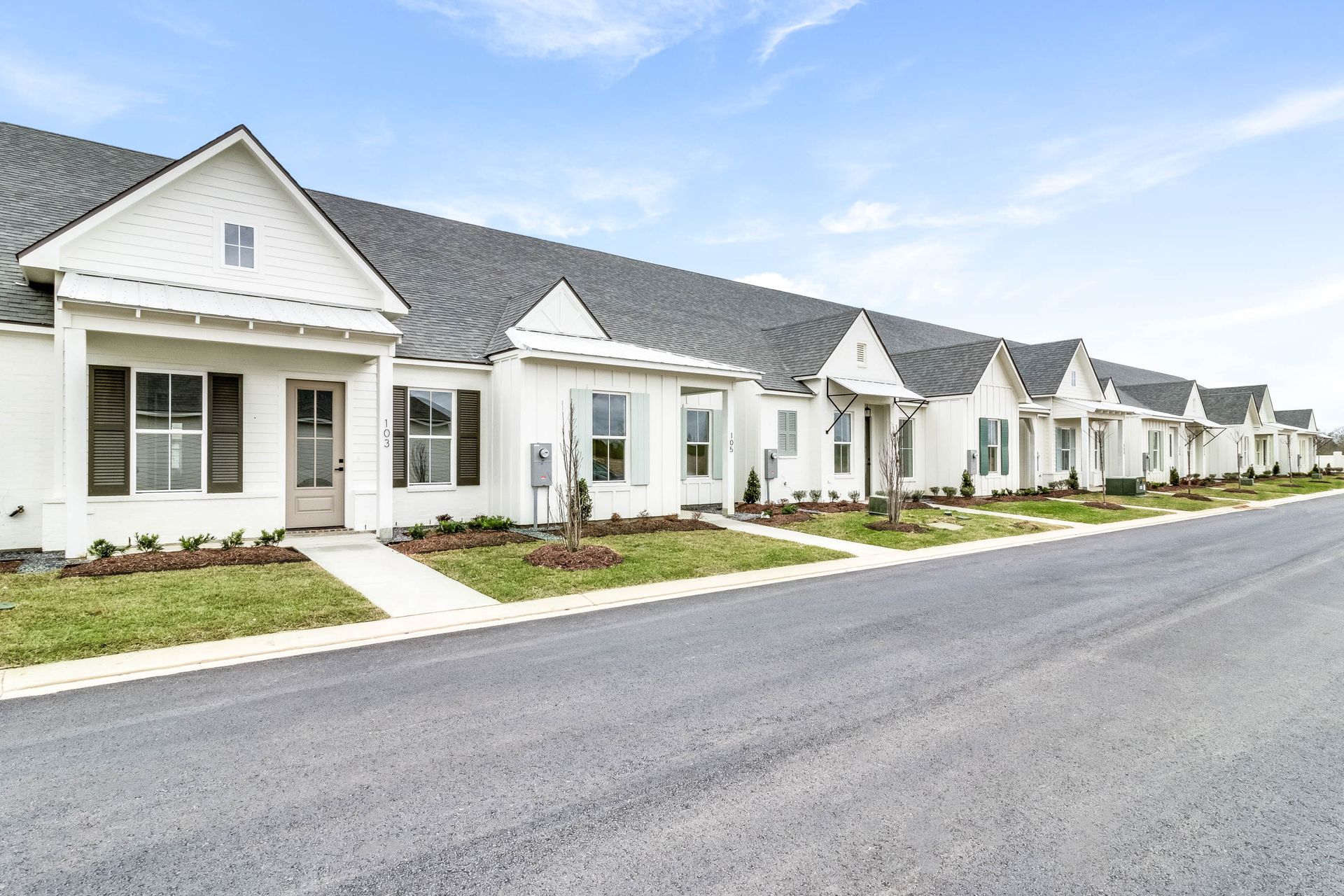 A row of white houses are lined up next to each other on a street.