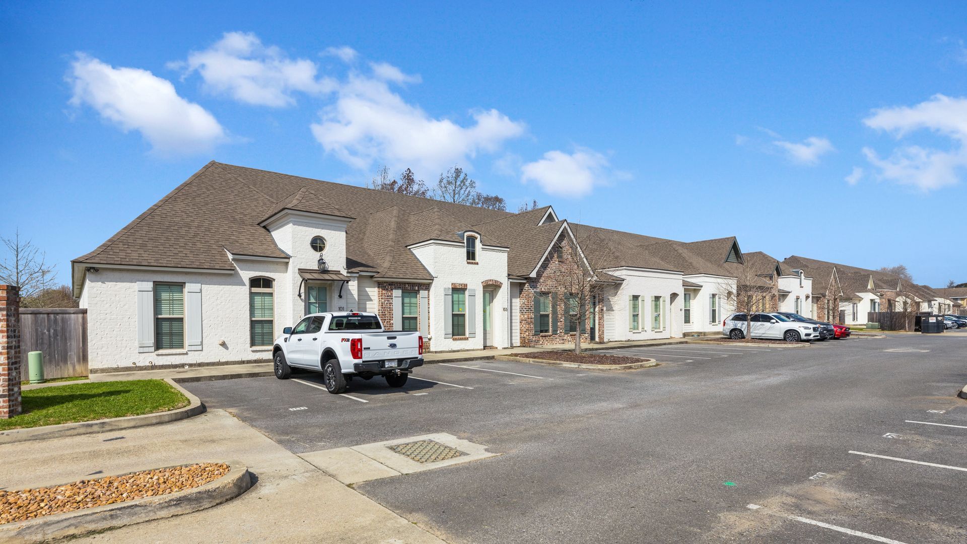 A row of houses with cars parked in front of them.