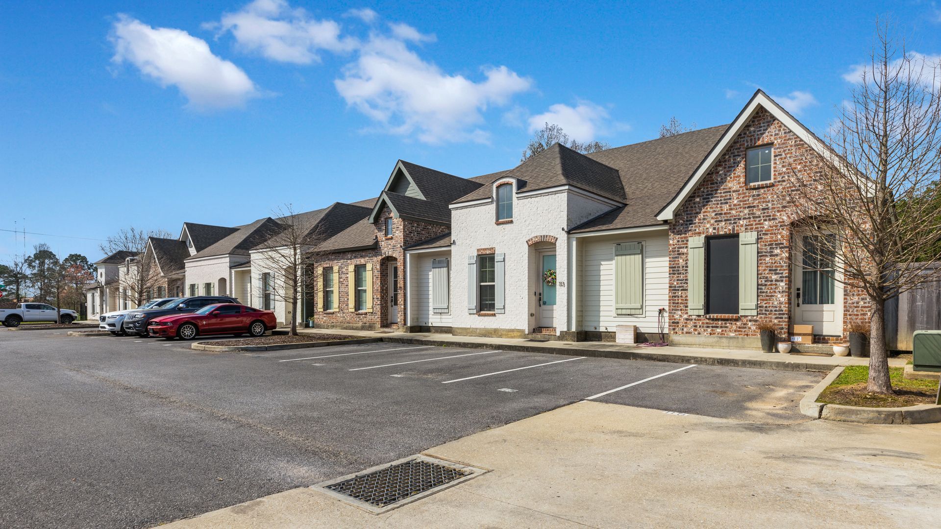 A row of houses with cars parked in front of them on a sunny day.