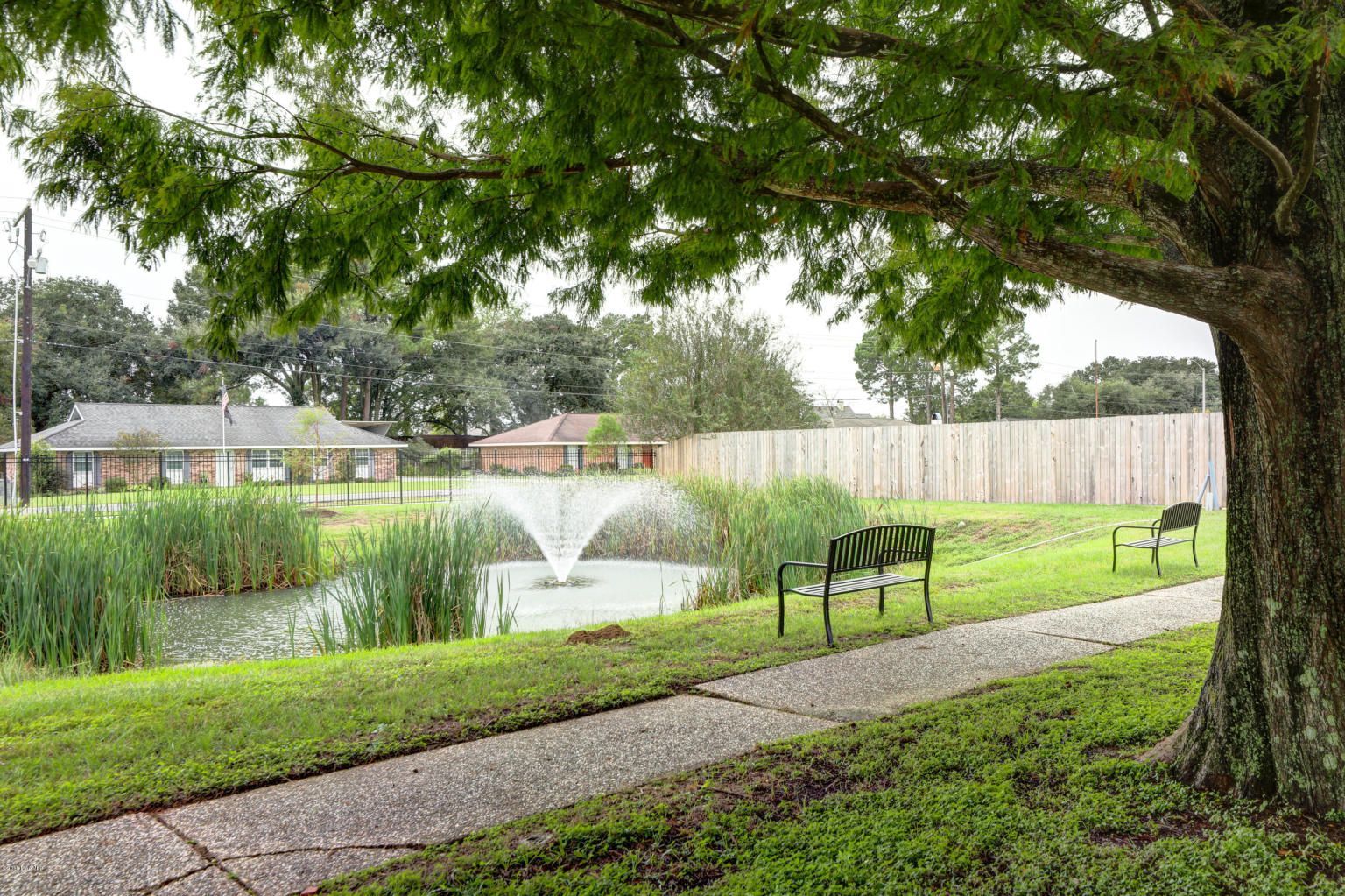 A park with a bench and a fountain in the middle of it.