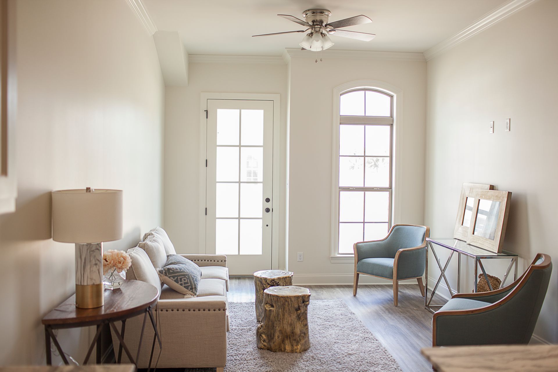 A living room with a couch , chairs , tables and a ceiling fan.