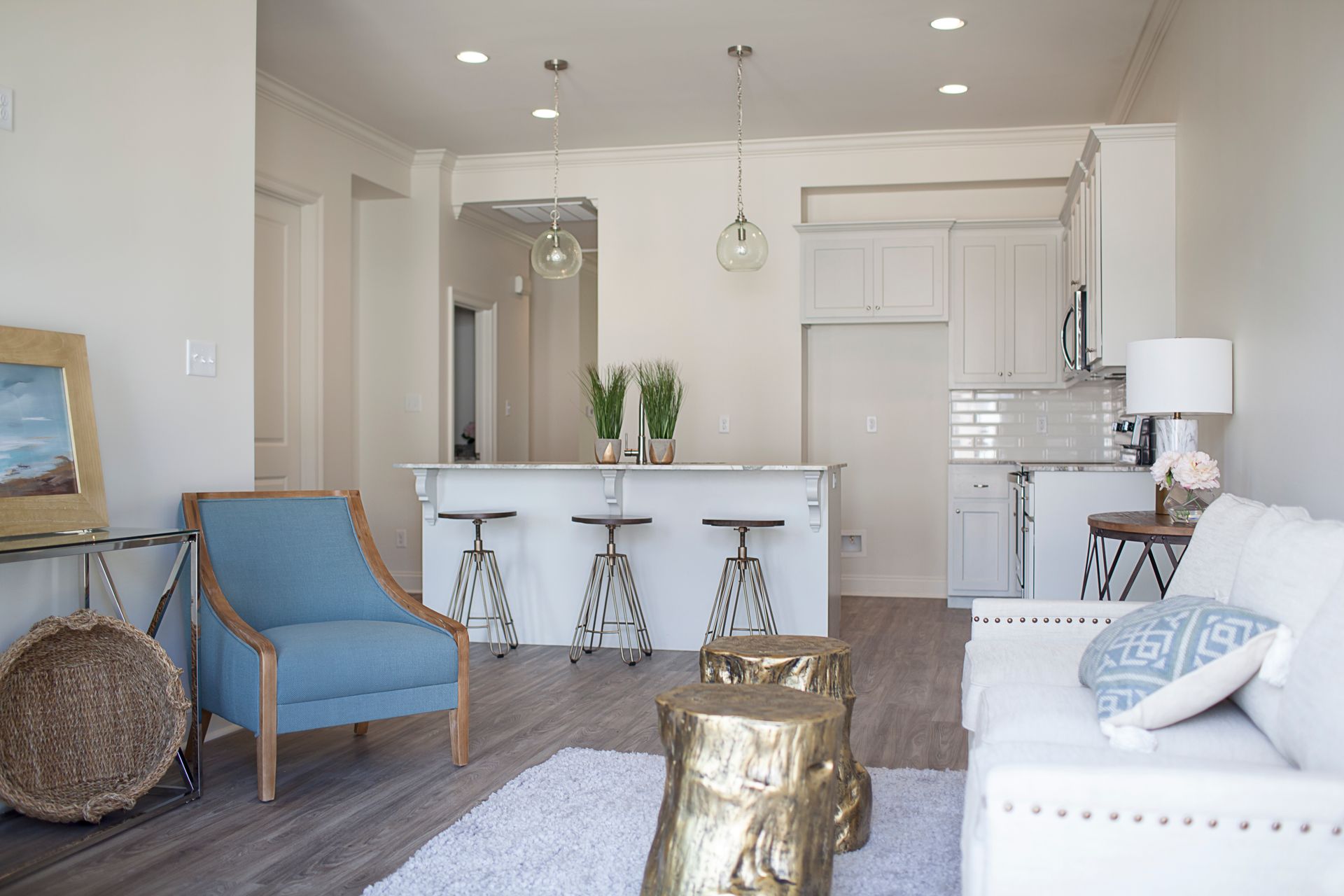A living room with a couch and chairs and a kitchen in the background.