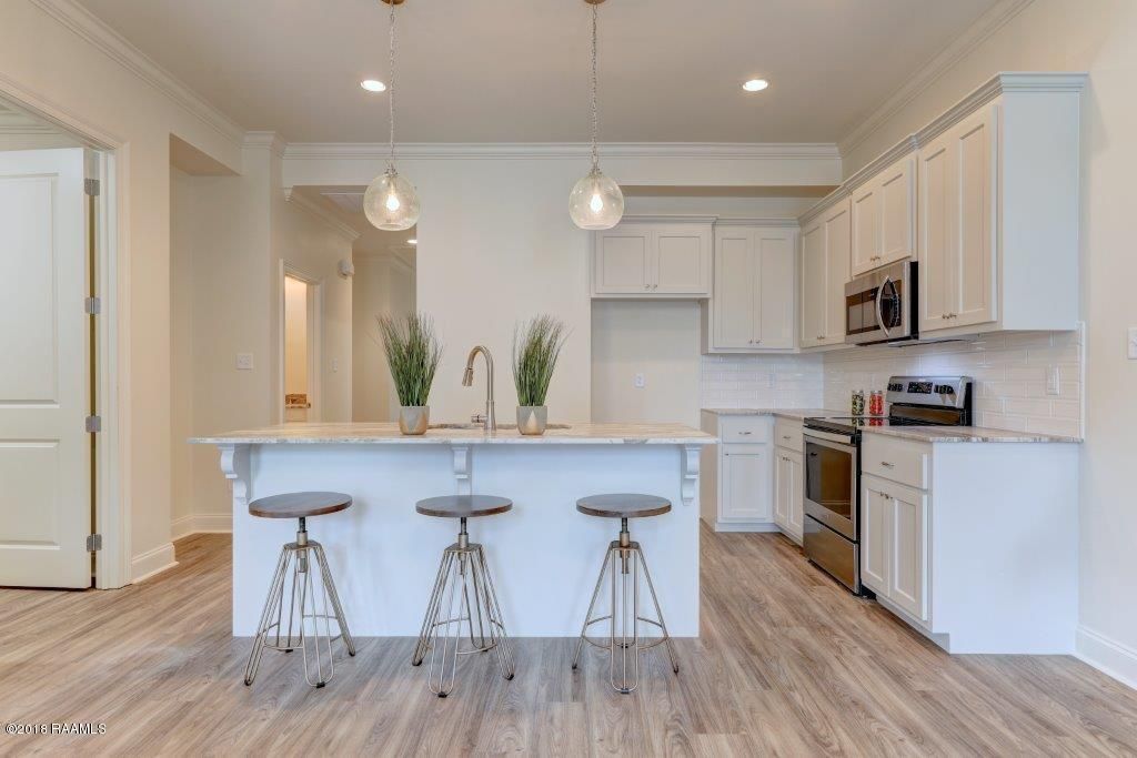 A kitchen with white cabinets , stainless steel appliances , and a large island.