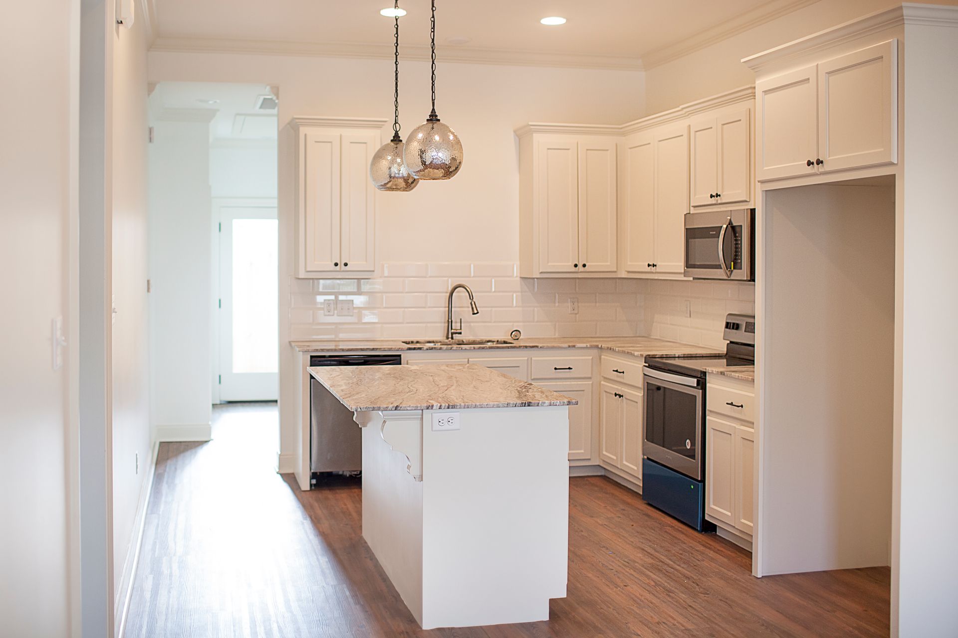 A kitchen with white cabinets , granite counter tops , stainless steel appliances and a large island.