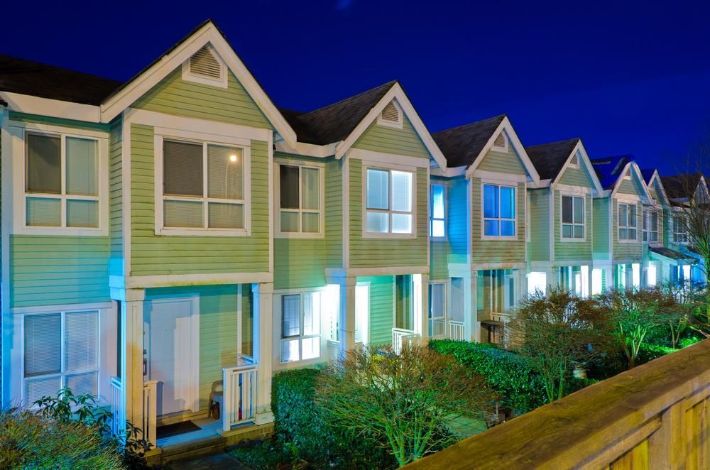 A Row of Green Houses Are Lit up At Night — Jarrett Lawrie Conveyancing in Parap, NT