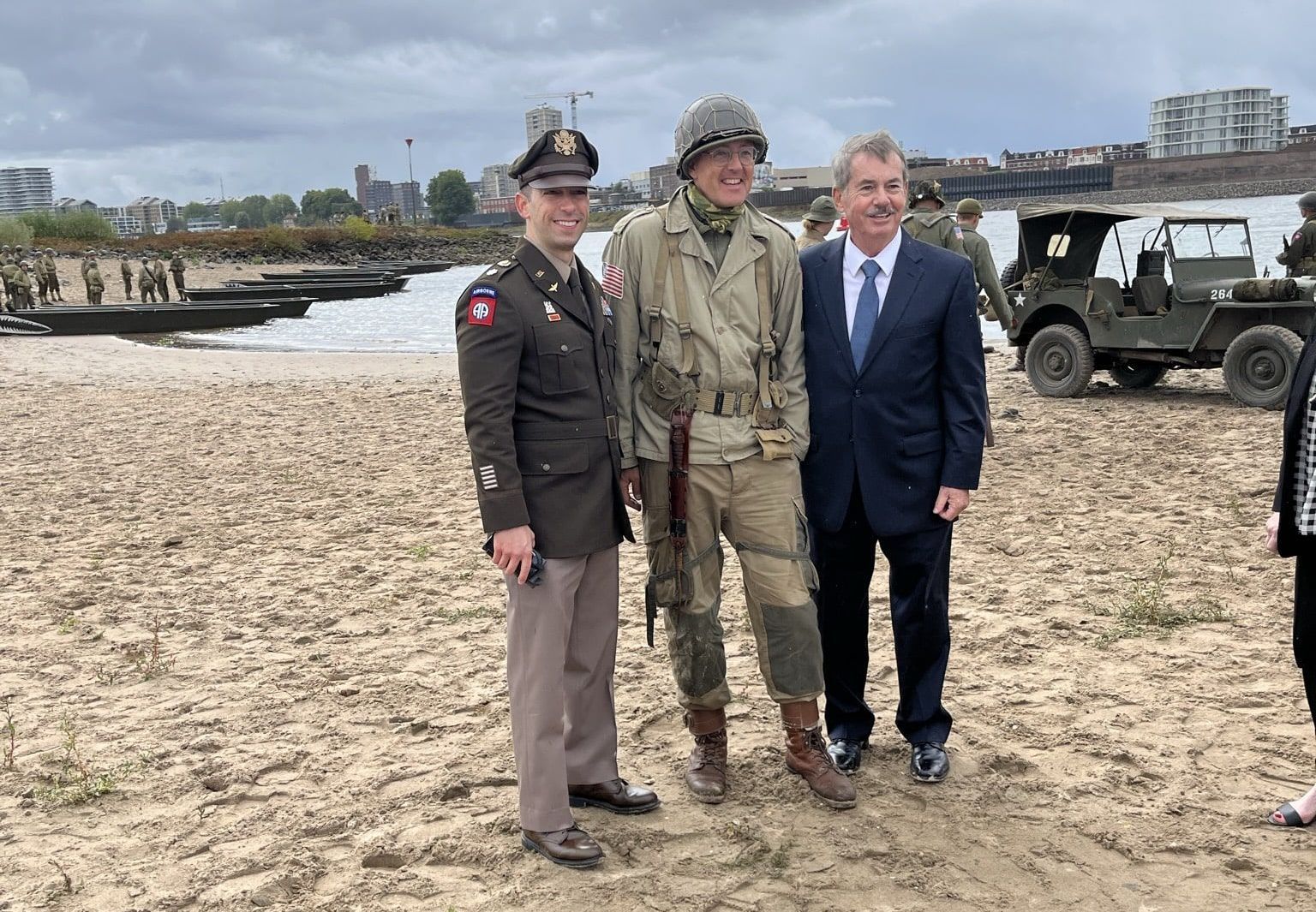 Drie mannen in militaire uniformen poseren voor een foto op het strand.