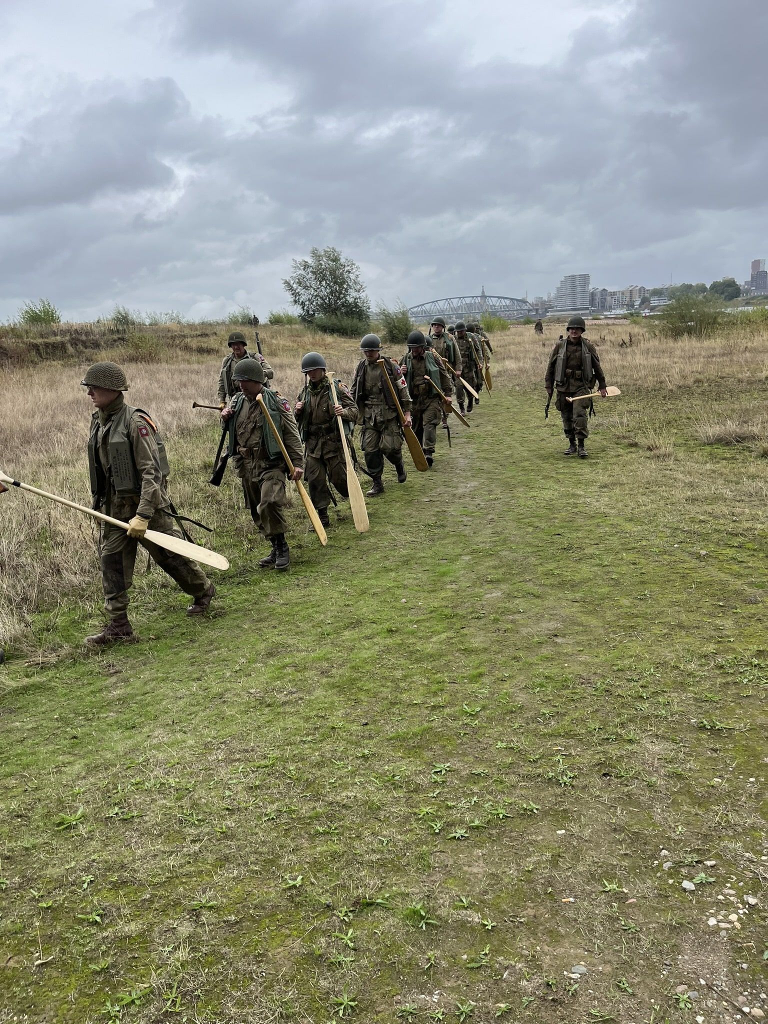 A group of soldiers are walking down a path in a field.