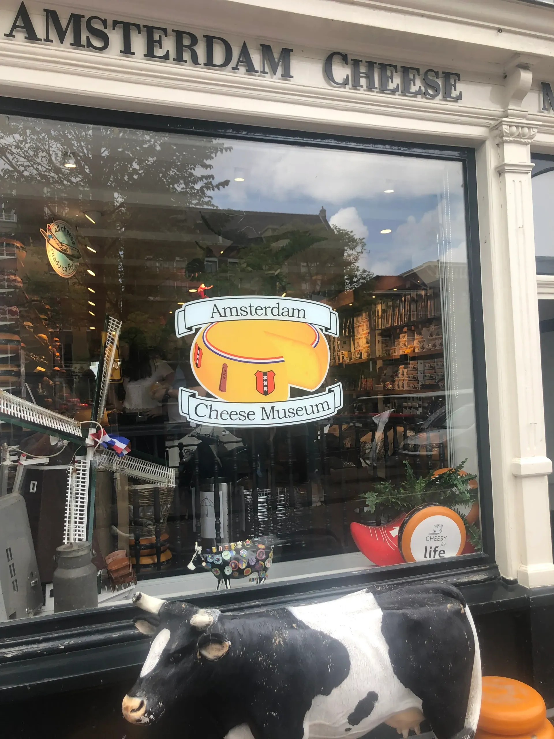 A cow statue is sitting in front of a store window.