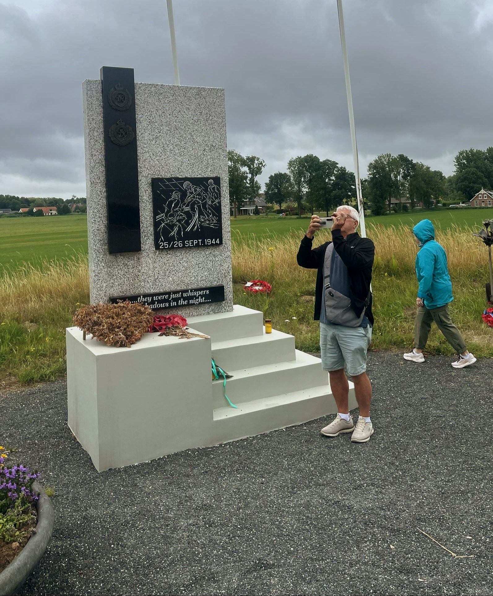A man is taking a picture of a monument in a field.