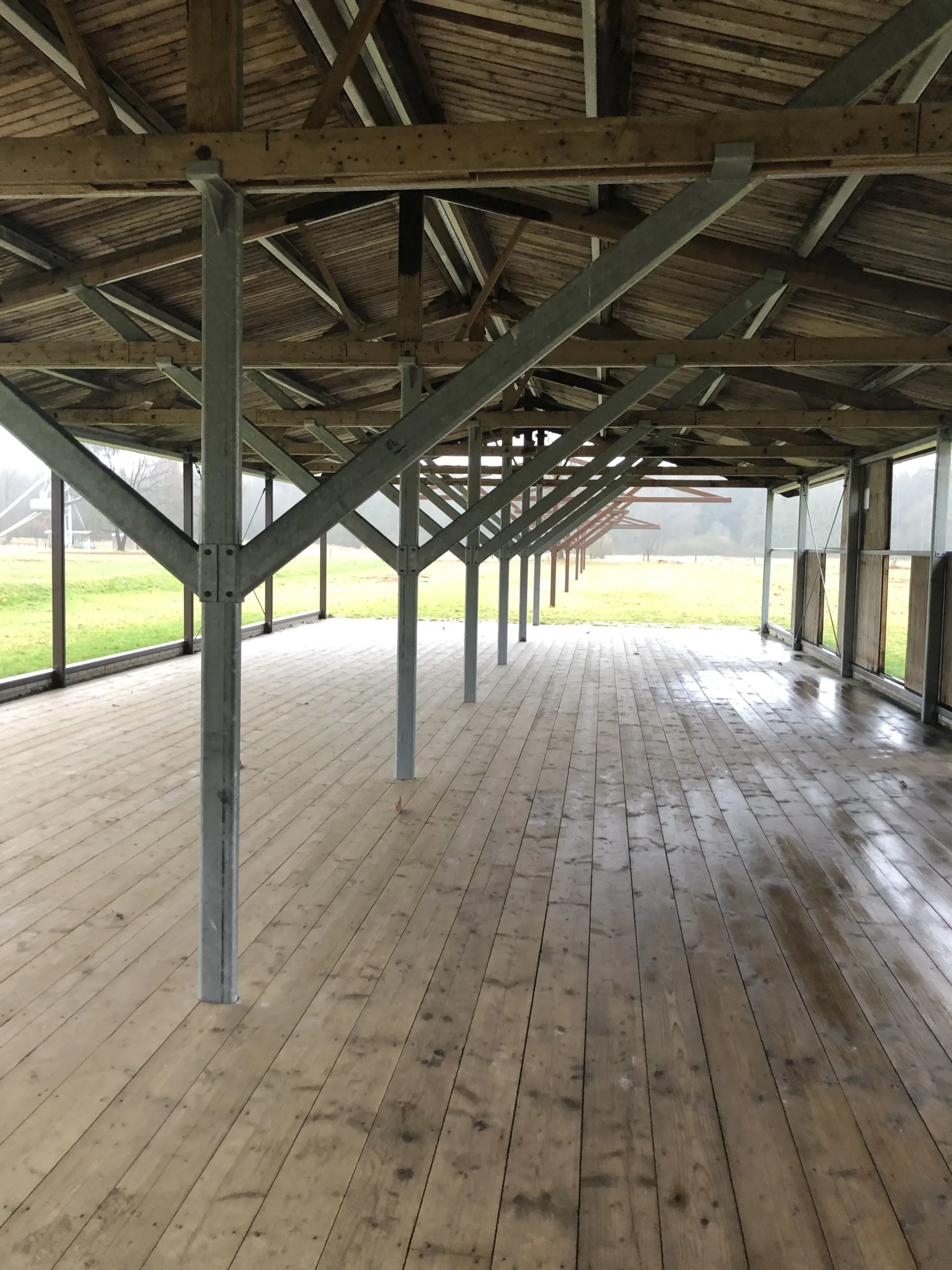Een groot leeg gebouw met een houten vloer en een dak, barak in Westerbork