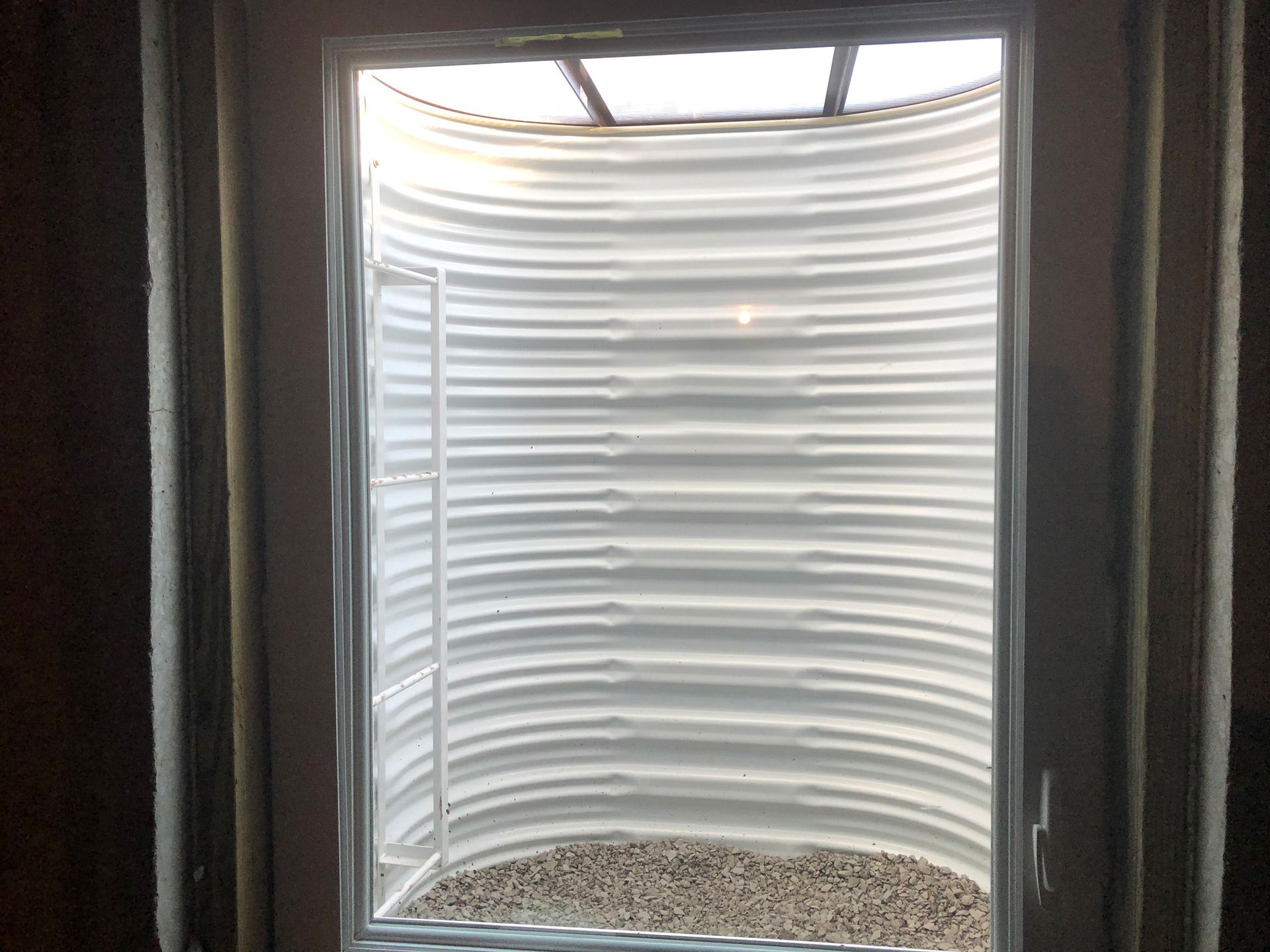 A window in a room with a door that looks like a tunnel.