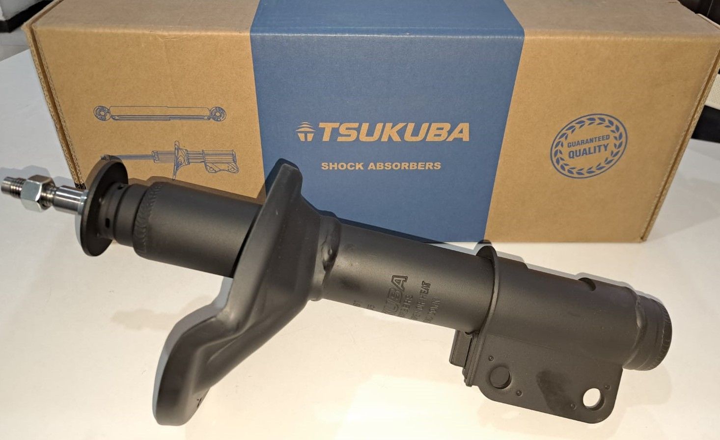 Amortiguador Tsukuba negro junto a su caja de cartón.
