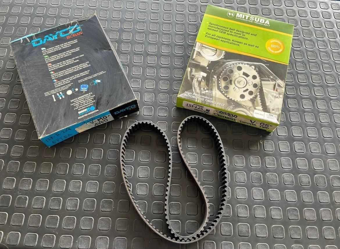 Dos cajas de piezas de automóvil y una correa de distribución sobre una superficie estampada.