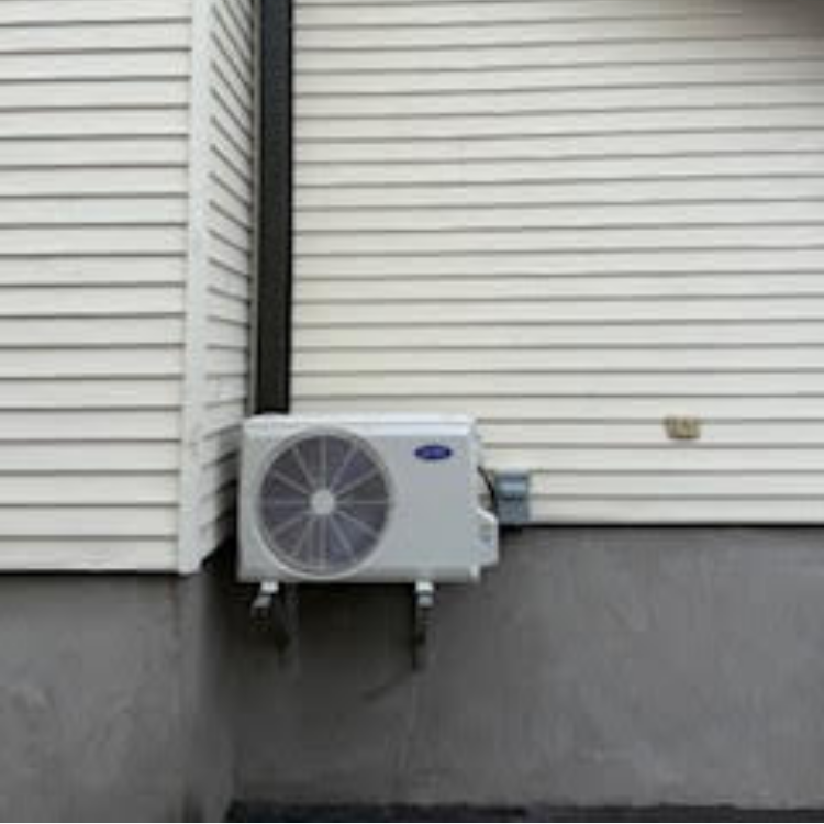 Un climatiseur blanc est posé sur le côté d'un bâtiment.