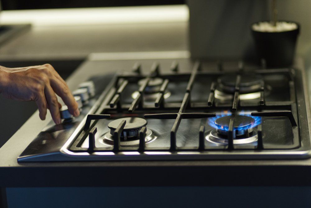 Une personne appuie sur un bouton d'une cuisinière à gaz.