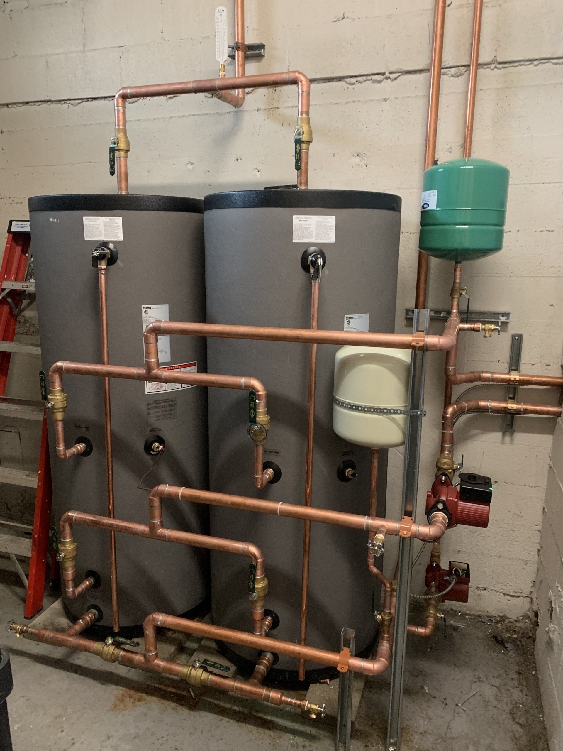 Trois chauffe-eau sont connectés à des tuyaux en cuivre dans une pièce