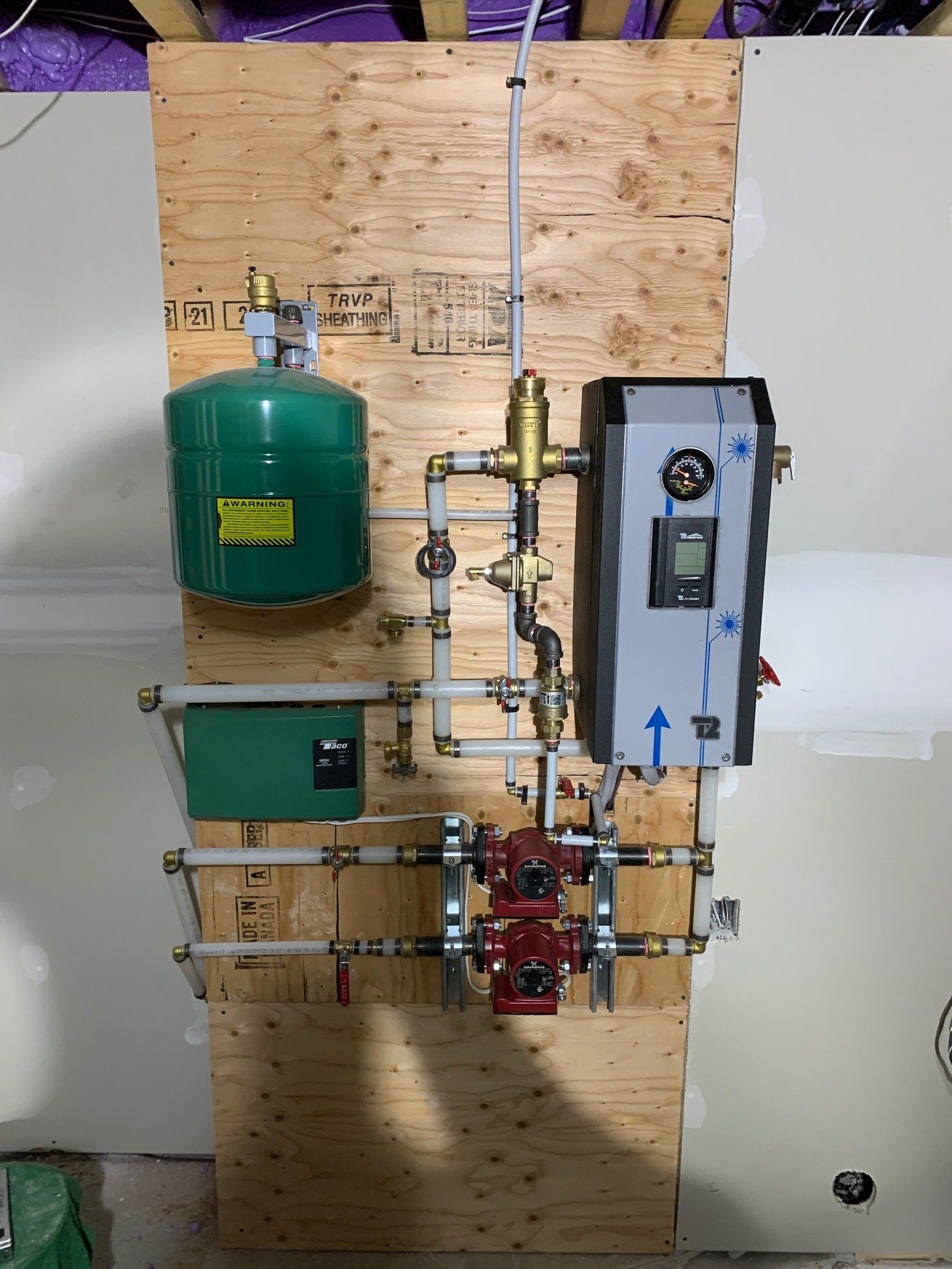 Un mur avec beaucoup de tuyaux et un réservoir vert dessus