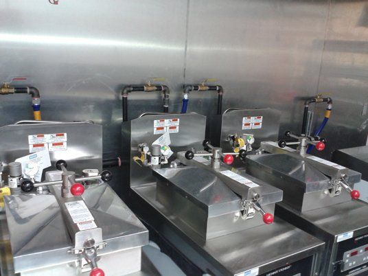 Une rangée de friteuses en acier inoxydable est alignée dans une cuisine