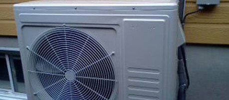 Un grand ventilateur est assis sur le côté d'un bâtiment.