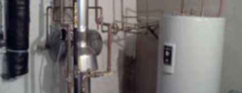 Une pièce avec un chauffe-eau et des tuyaux sur le mur.