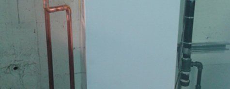 Des tuyaux en cuivre sont reliés à un mur blanc dans une pièce.