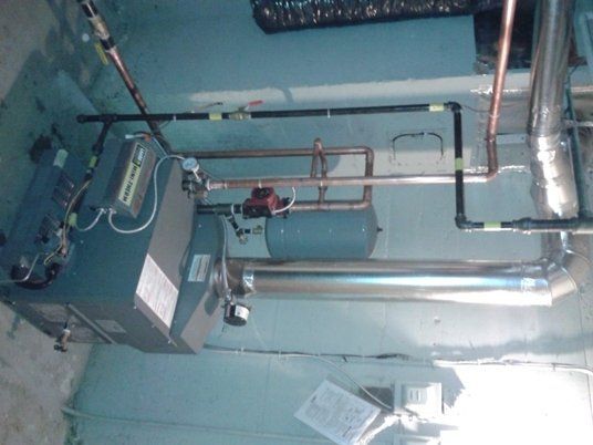 Une pièce avec une chaudière et des tuyaux suspendus au plafond