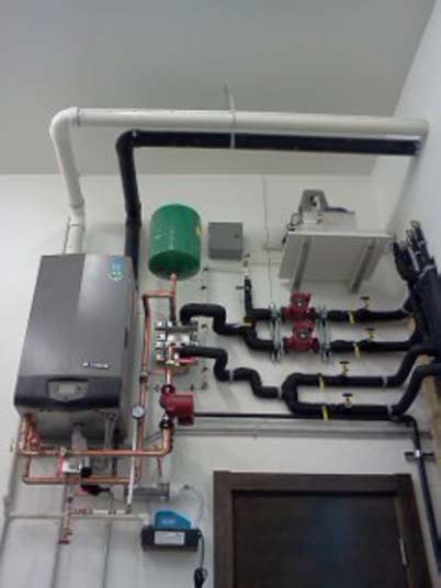 Une pièce avec une chaudière et des tuyaux sur le mur