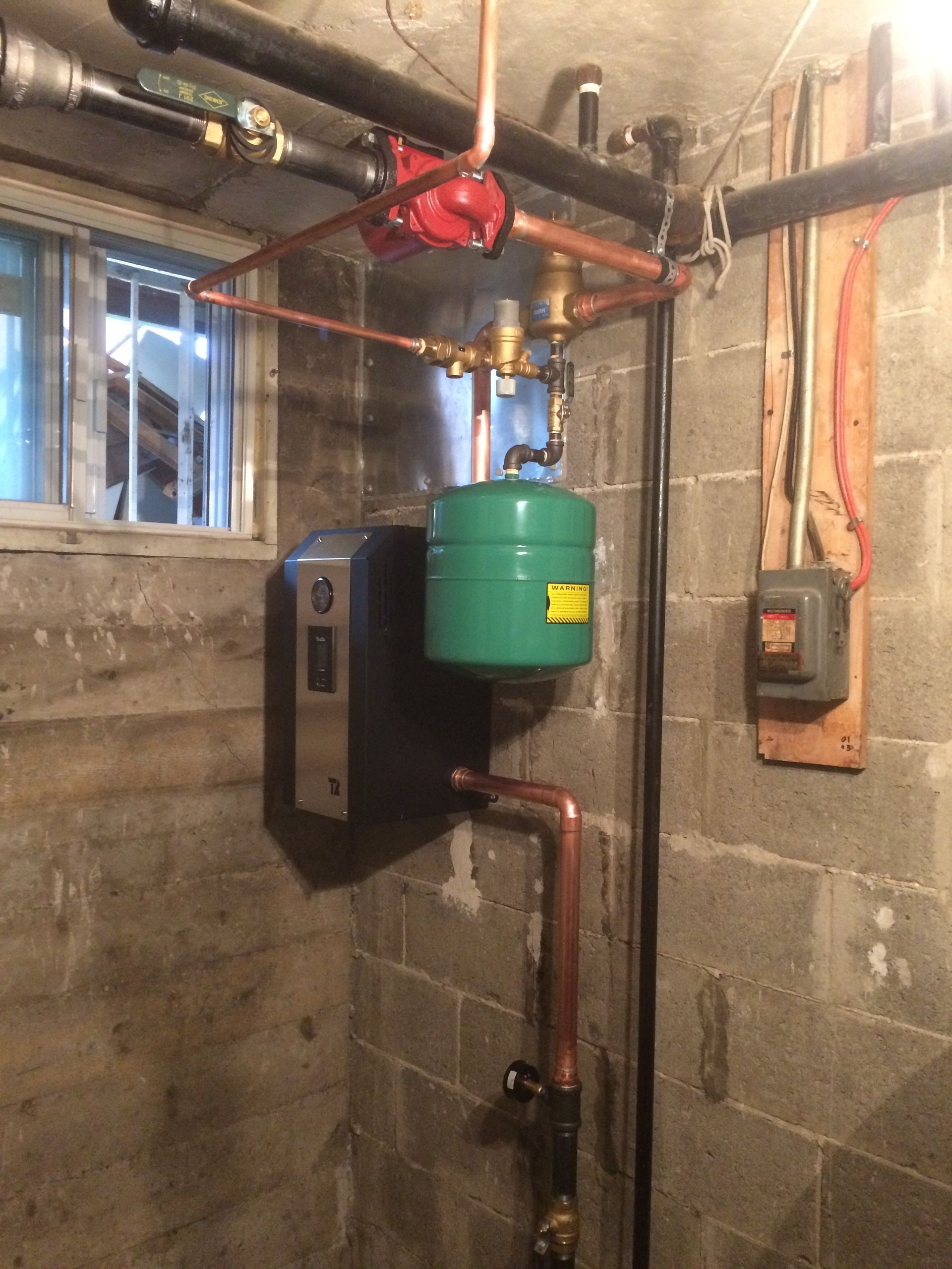 Un réservoir vert est suspendu au plafond dans un sous-sol