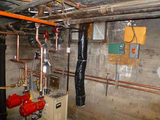 Une pièce remplie de nombreux tuyaux et d'une chaudière.
