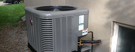 Un grand climatiseur est placé sur le côté d'un bâtiment à côté d'une fenêtre.