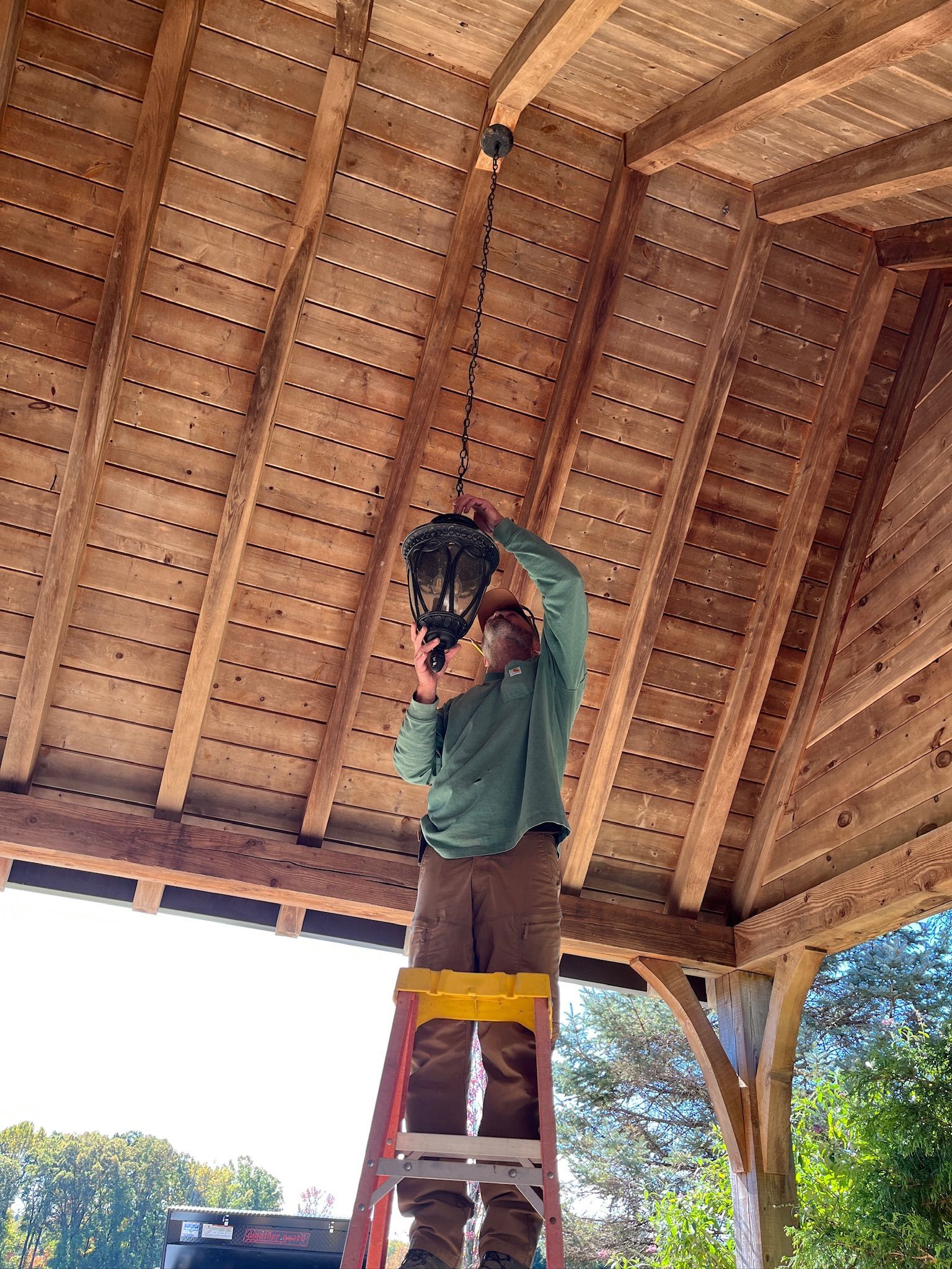 A person is fixing a chandelier with a screwdriver.
