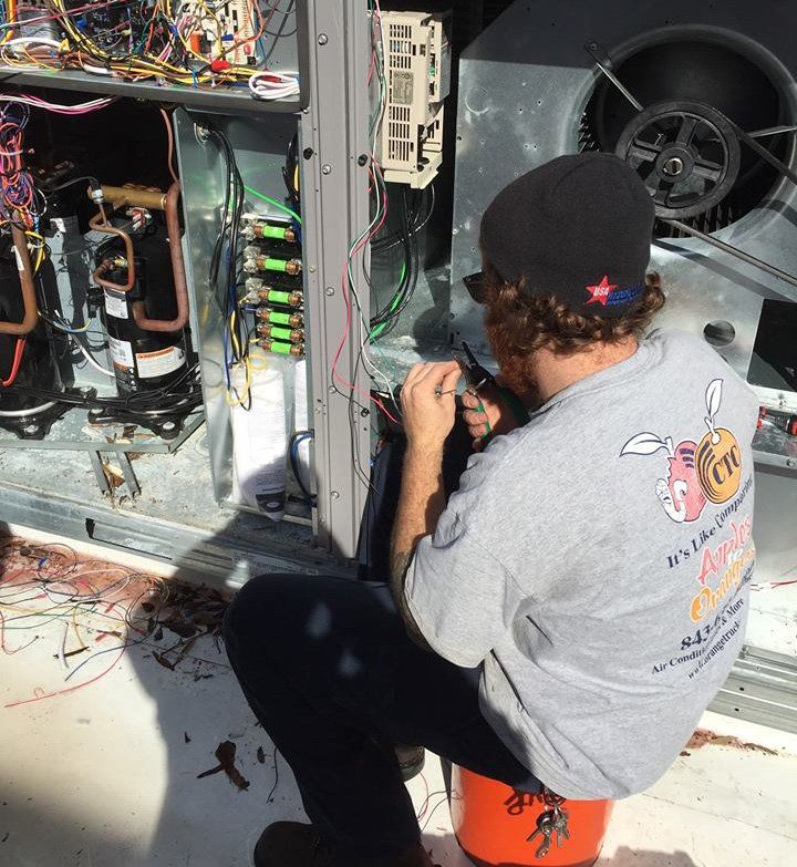 Carolina Temperature Control HVAC technician repairing an outdoor heating and cooling system unit