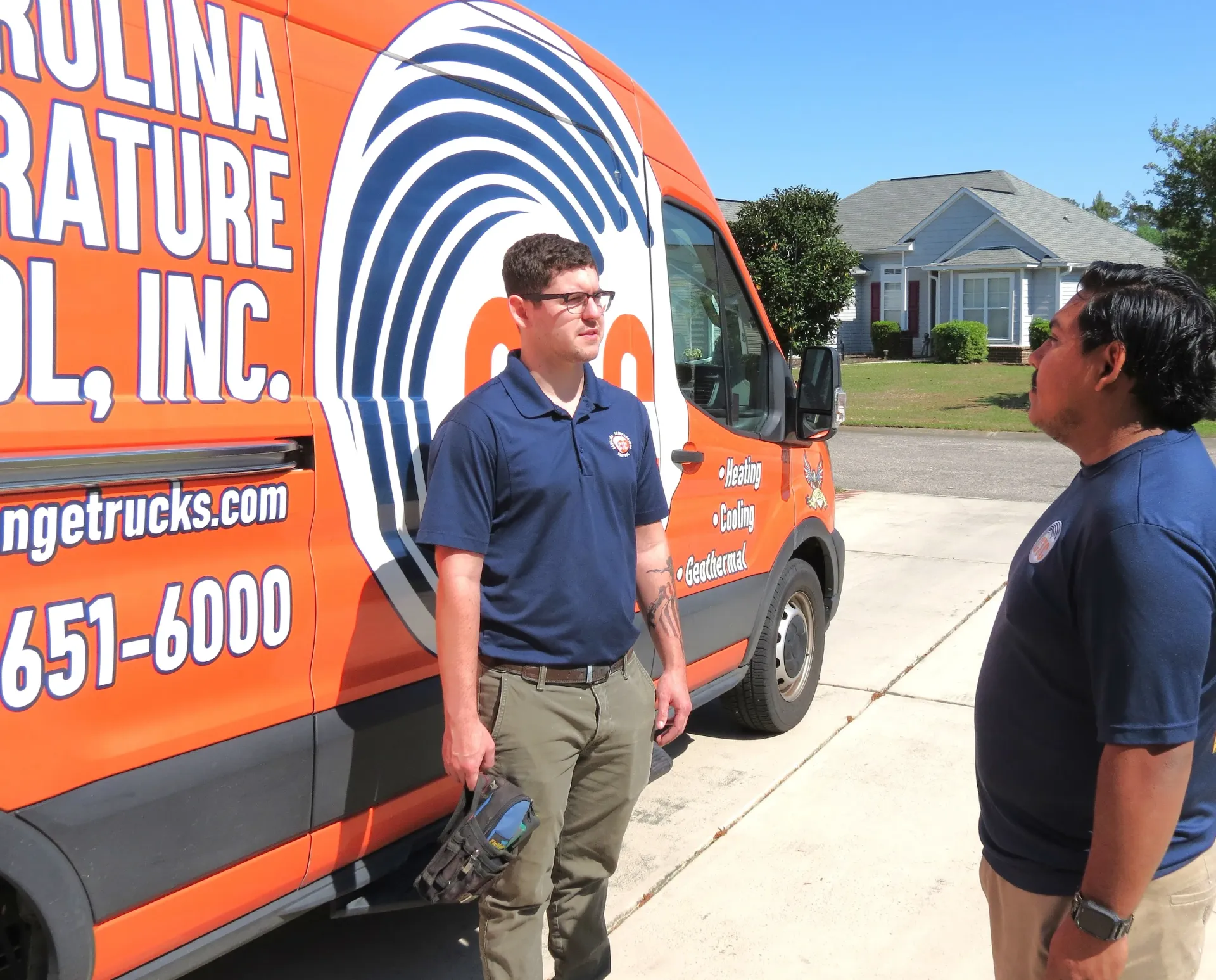 Two HVAC technicians standing in front of a Carolina Temperature Control service van