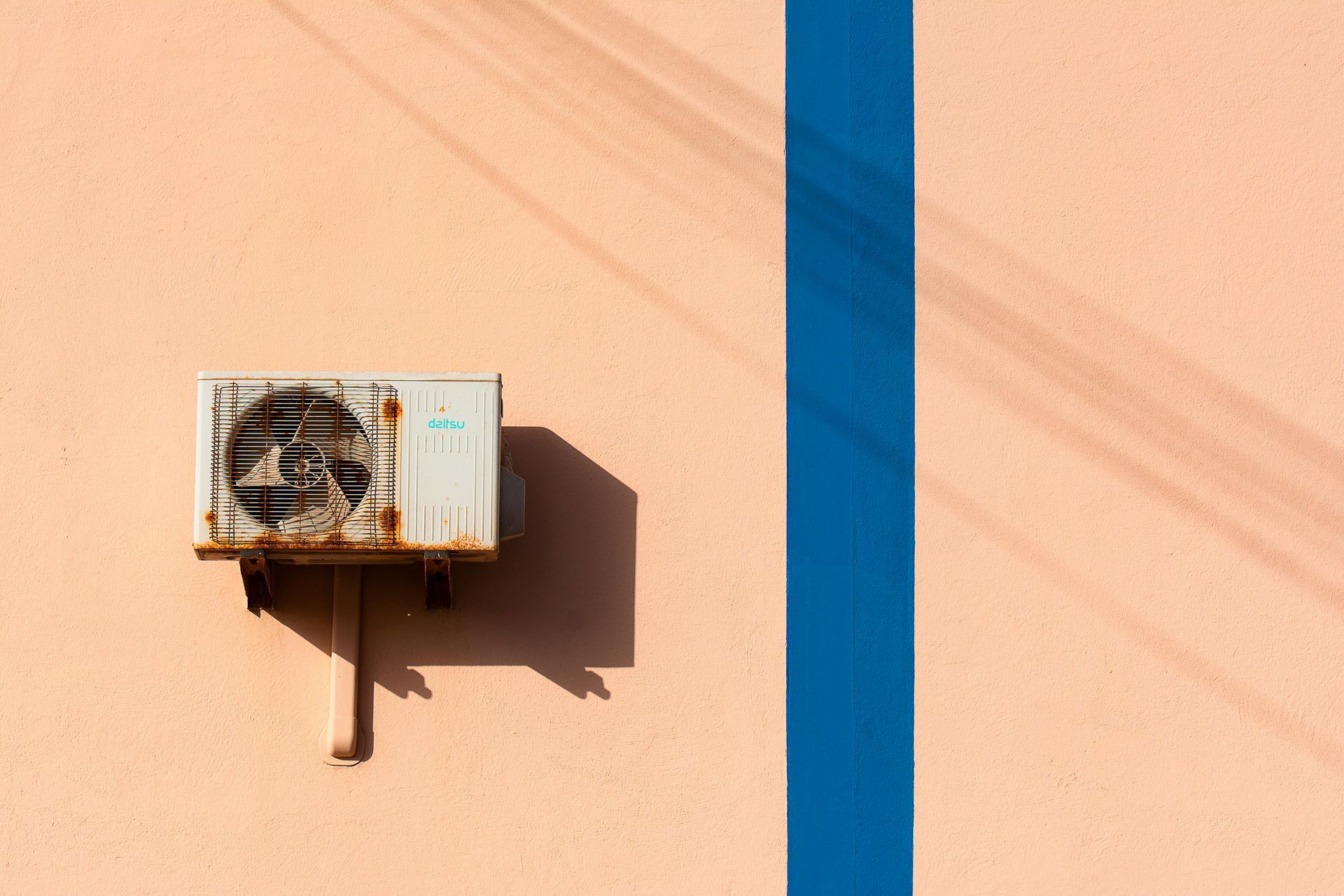 A broken and rusty air conditioner is mounted on the side of a building.