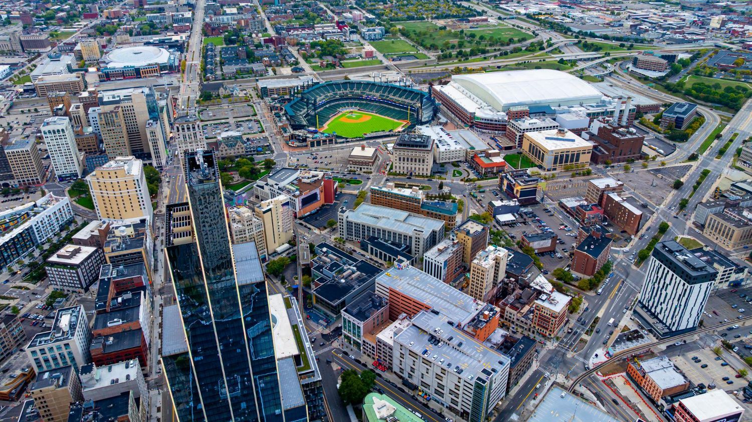 Aerial view of a city with a baseball stadium, an arena, and numerous buildings.