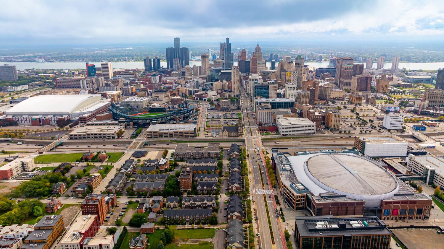 Detroit skyline view with stadiums, buildings, and residential areas under a cloudy sky.