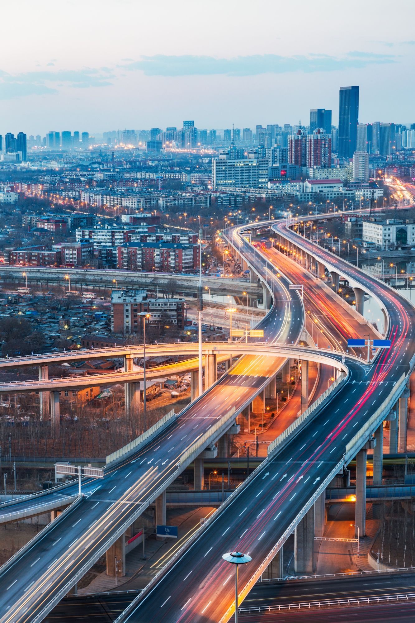A woman is carrying a little girl on her shoulders in a field at sunset.