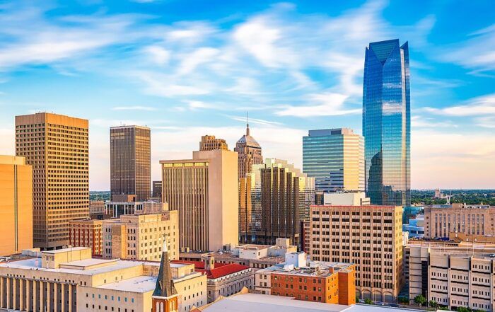Oklahoma City skyline with skyscrapers against a blue sky, some buildings in shades of gold.