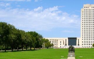 North Dakota State Capitol building in Bismarck, with green lawn and trees.